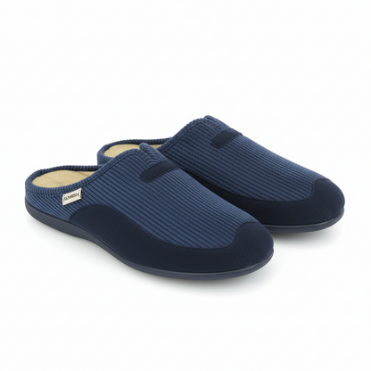 Paire de pantoufles homme bleu marine portées avec pantalon beige, sur terrasse en bois – style détente et confort